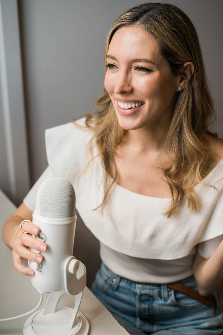 Tamara Ashworth laughing while holding a white podcast microphone.